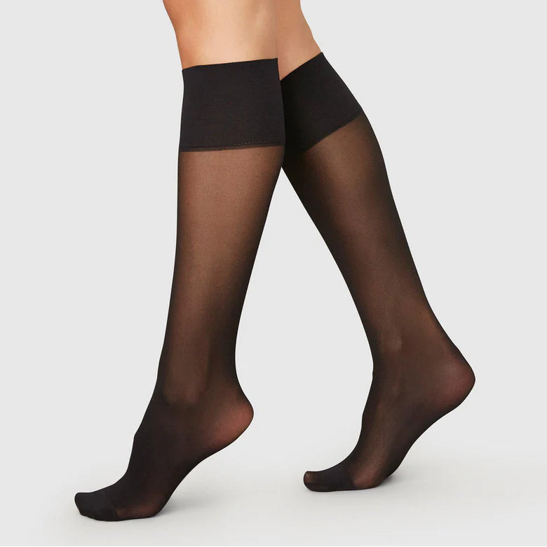 Black sheer socks worn by a person on a white background