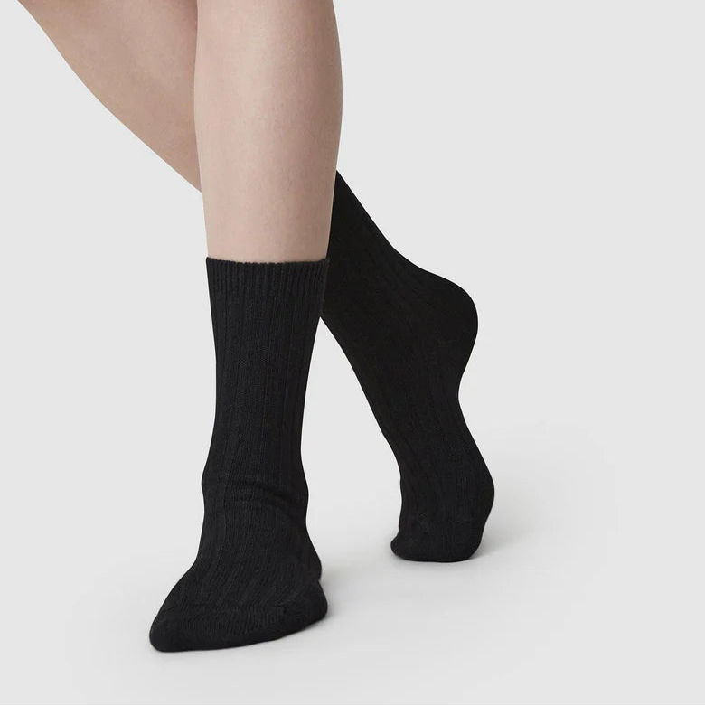 Black socks worn by a person on a light gray background