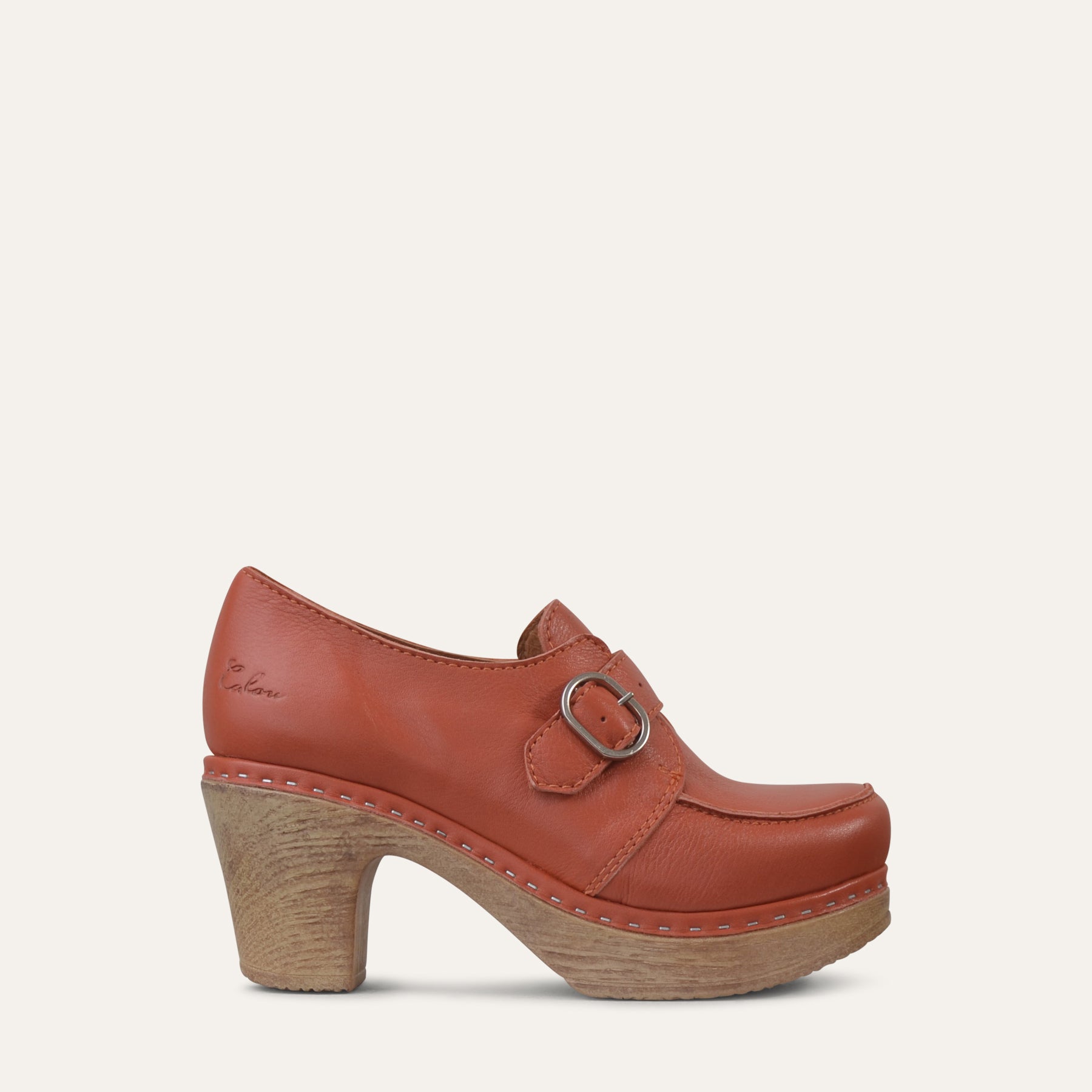 Burnt orange leather clog shoe with wood-look heel on a light beige background