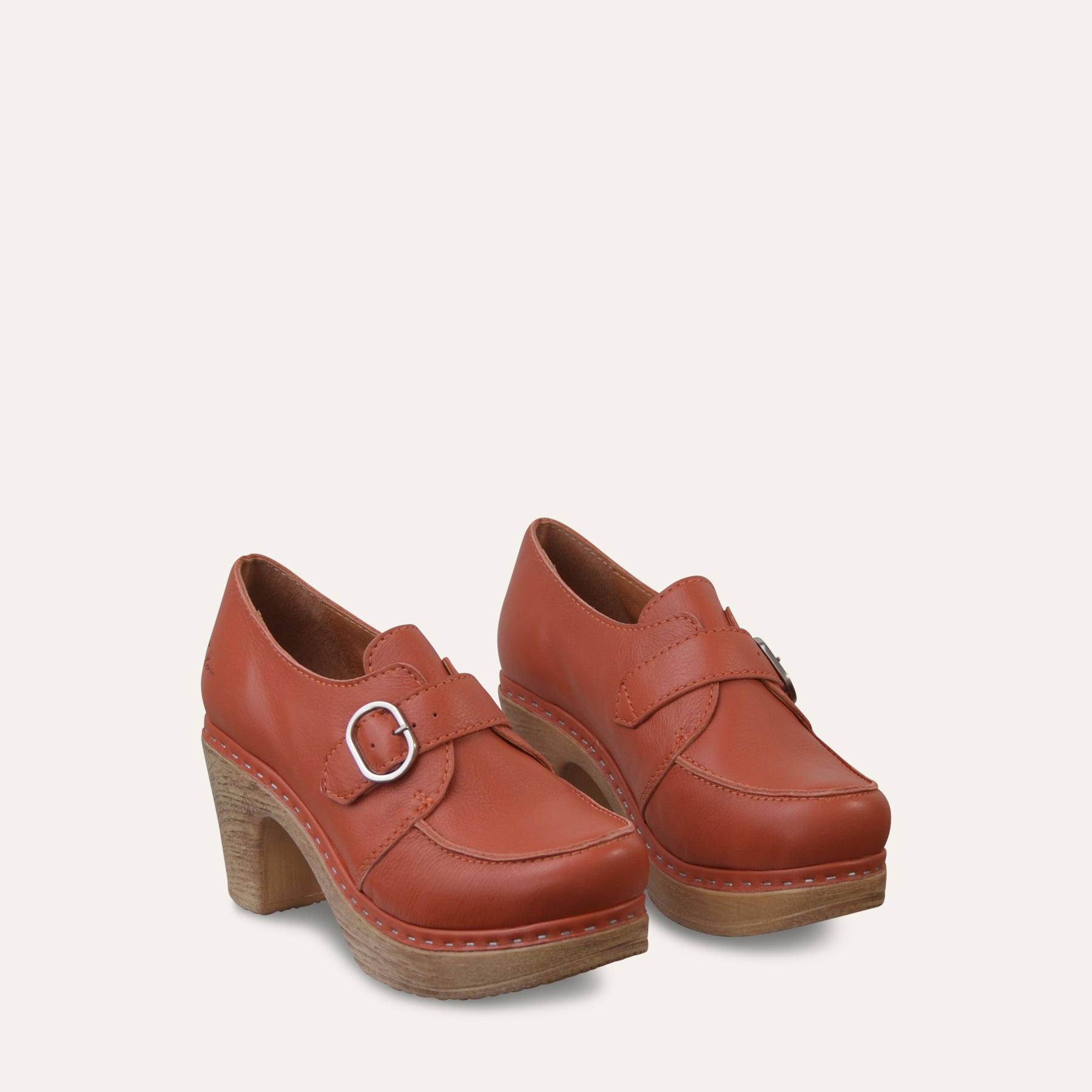 Pair of red clog shoes with vintage style wood-like soles on a beige background
