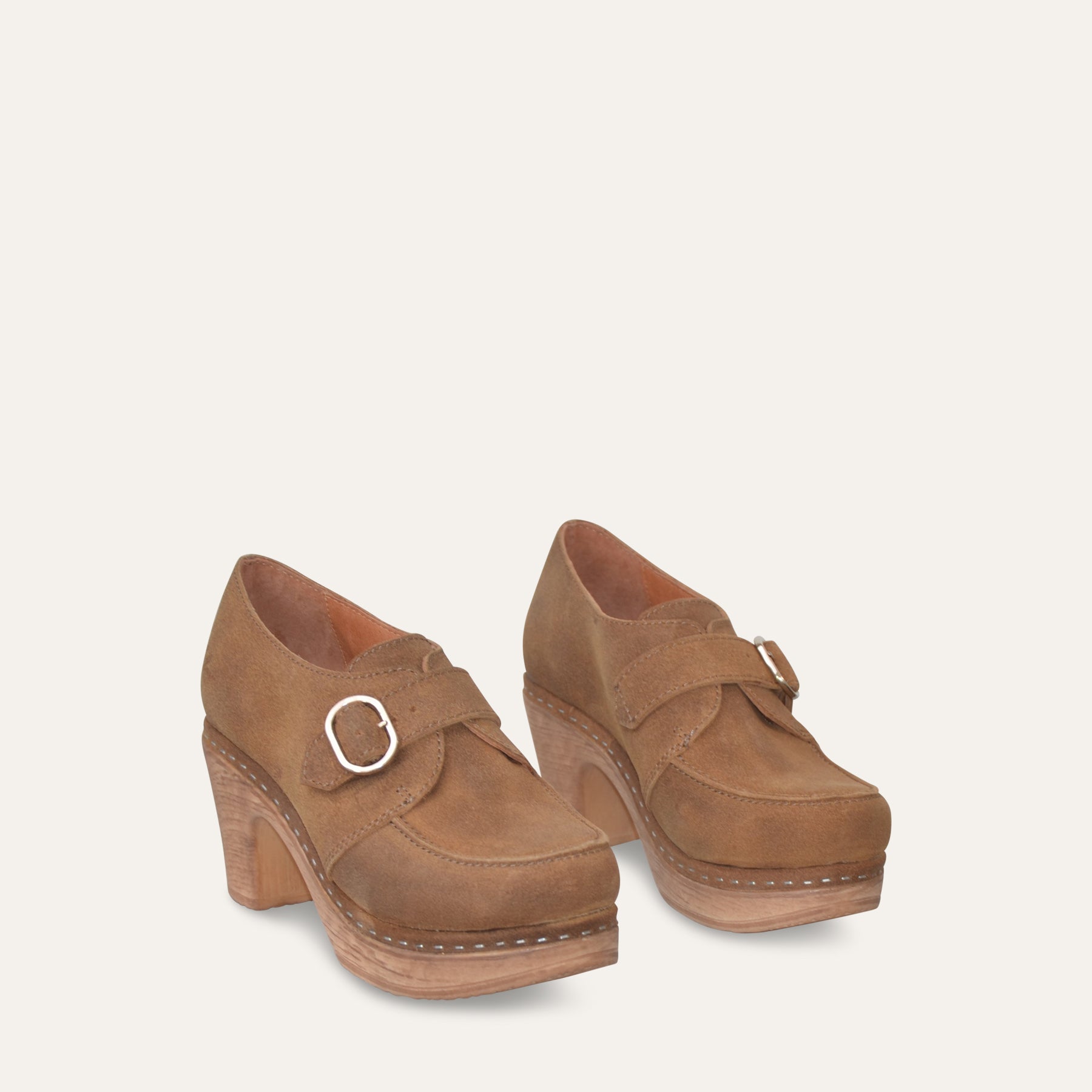 Pair of tan nubuk shoes with buckles on a light beige background