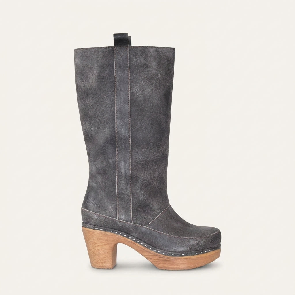 A dark gray distressed suede knee-high boot with a light brown wood-look block heel and platform, shown from a side profile against a light cream background.