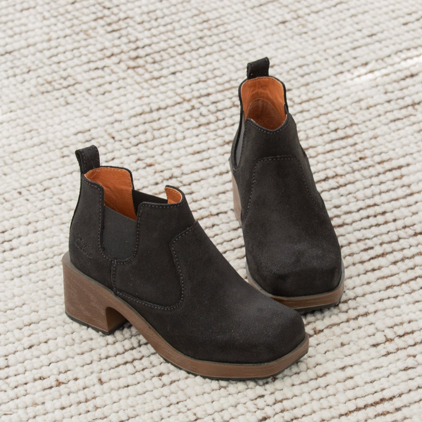 Pair of black ankle boots on a textured white surface