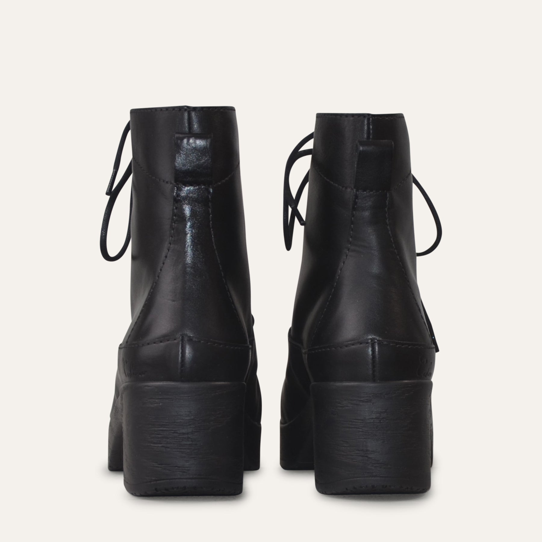 Pair of black leather platform boots on a light gray background