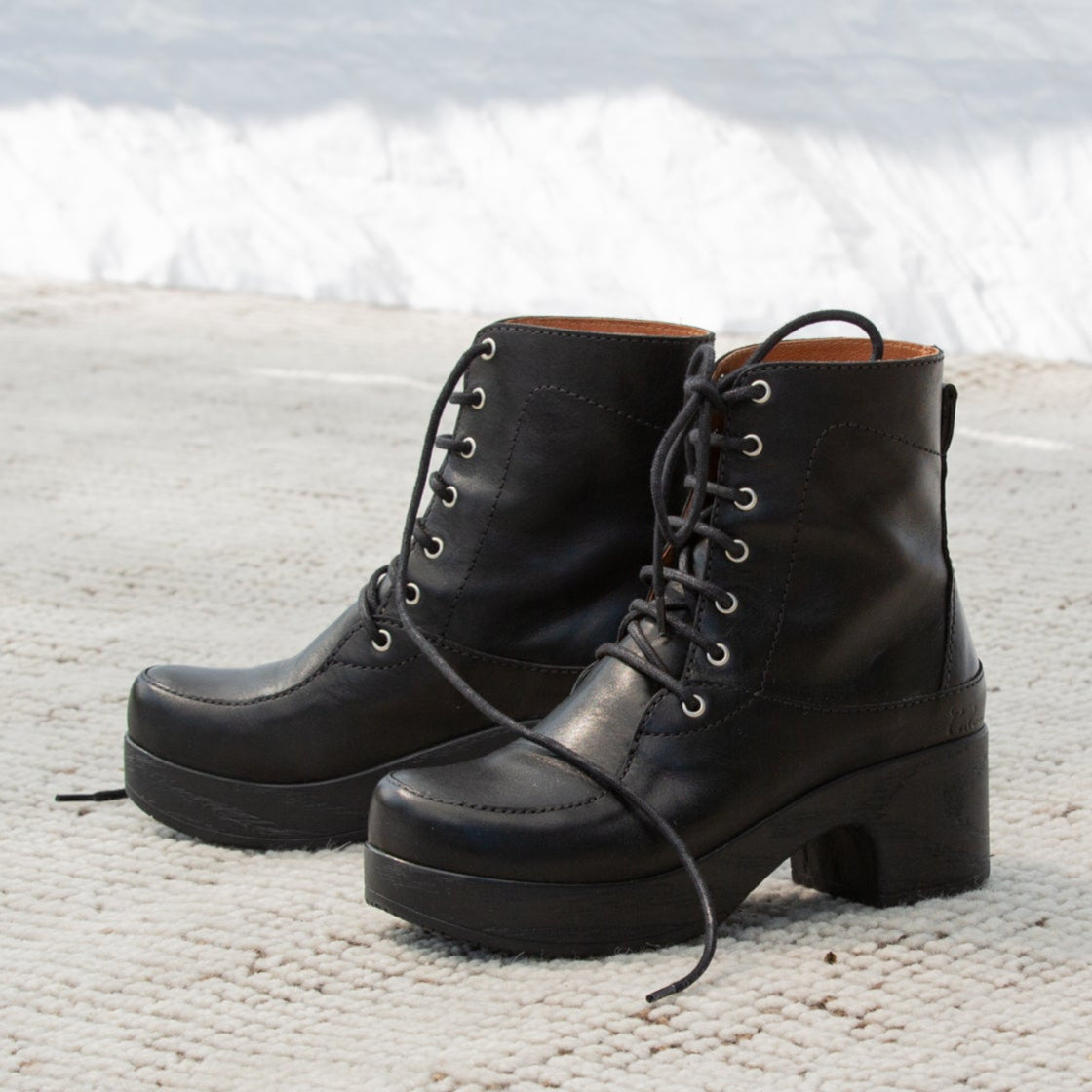 Pair of black leather boots on a textured surface with a blurred white background