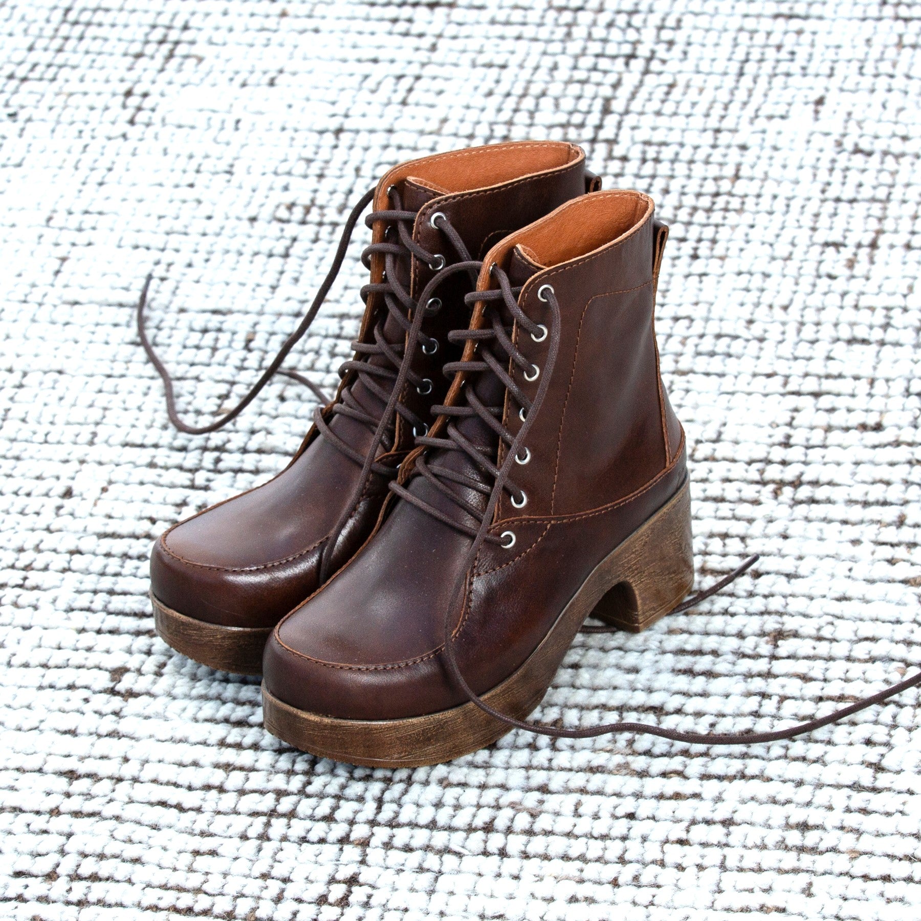 Pair of brown leather boots on a textured white surface