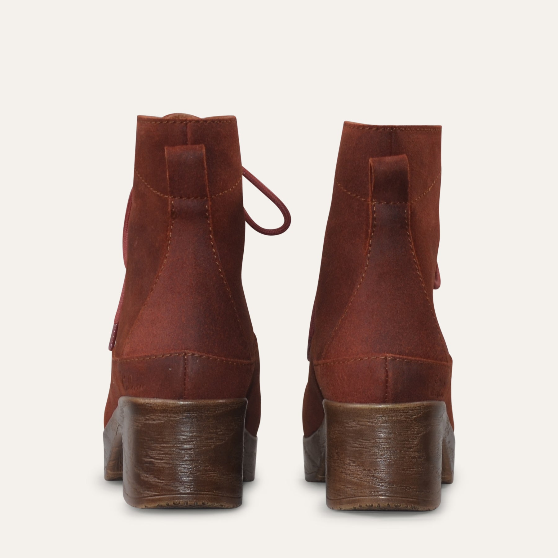 Pair of rust brown suede boots on a light gray background