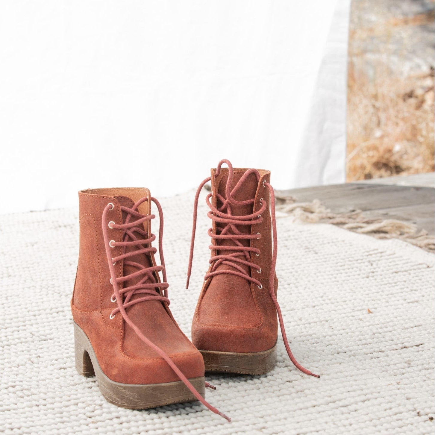 Pair of brown suede boots with laces on a textured surface