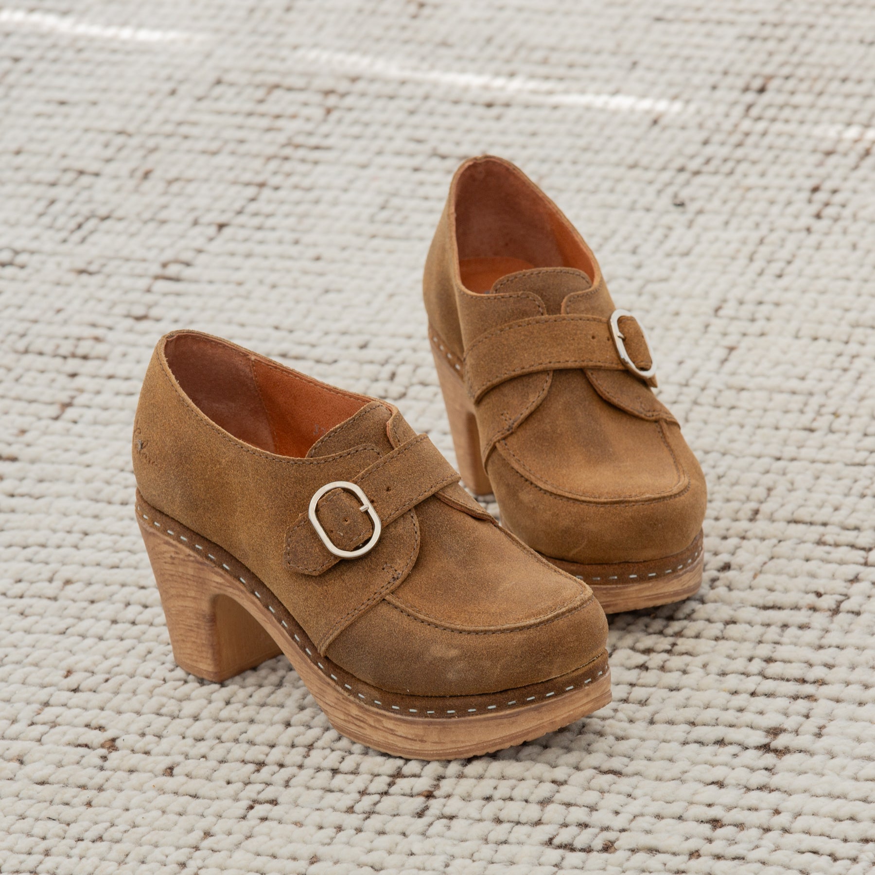 Pair of brown suede shoes with buckles on a textured surface