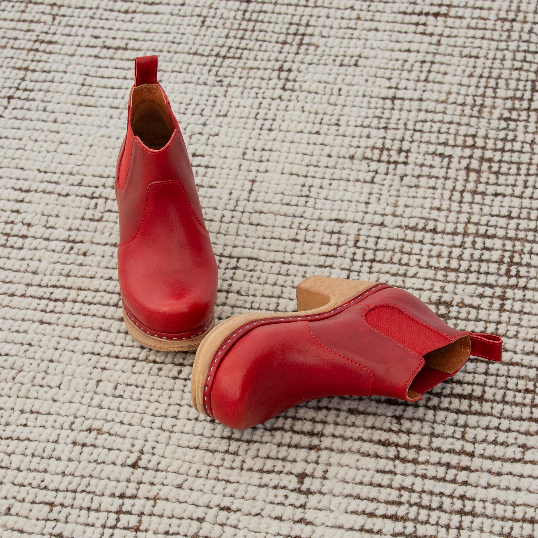 Red leather boots on a textured beige surface