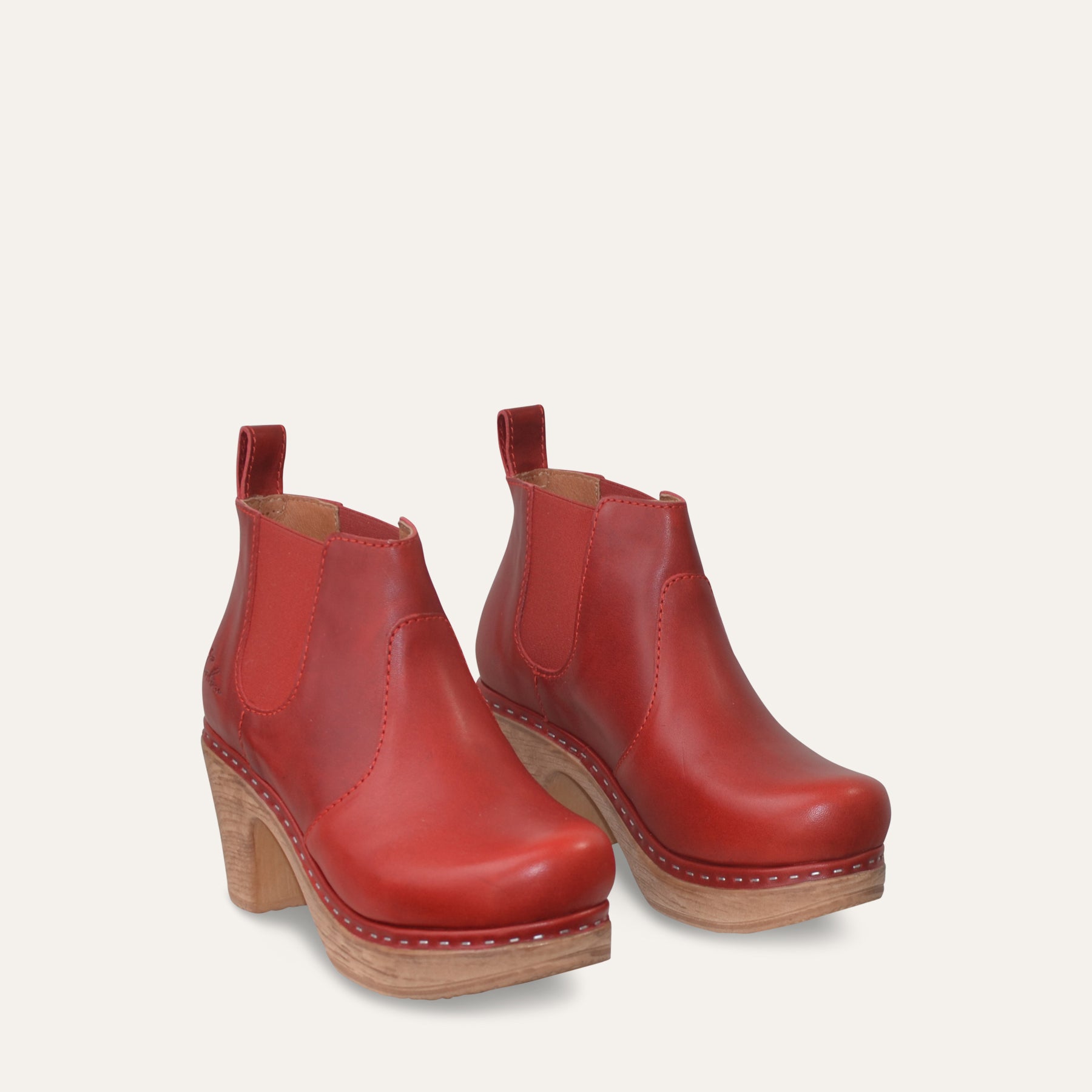 Red leather ankle boots with wood-like soles on a light beige background