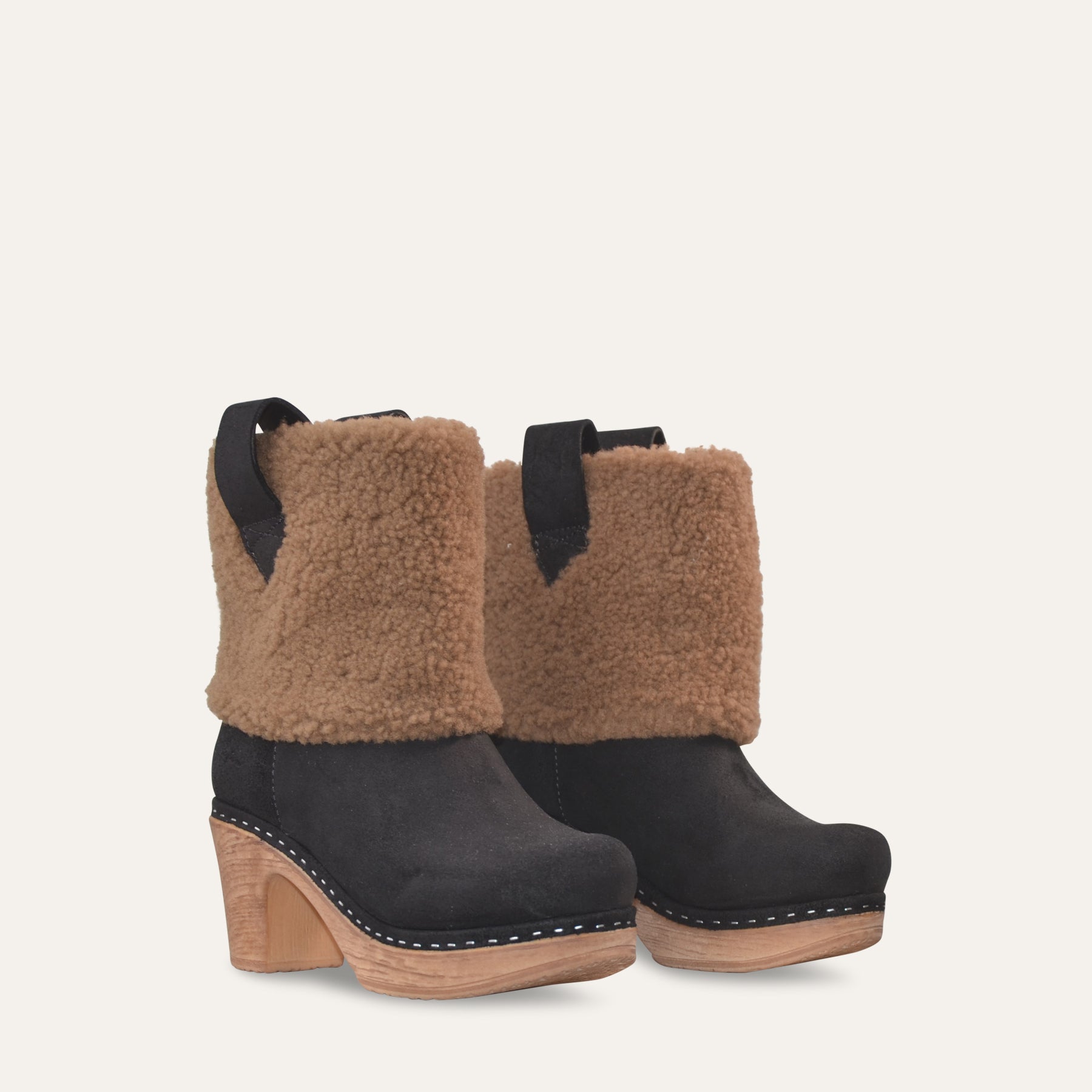 Black boots with brown shearling detail on a light gray background
