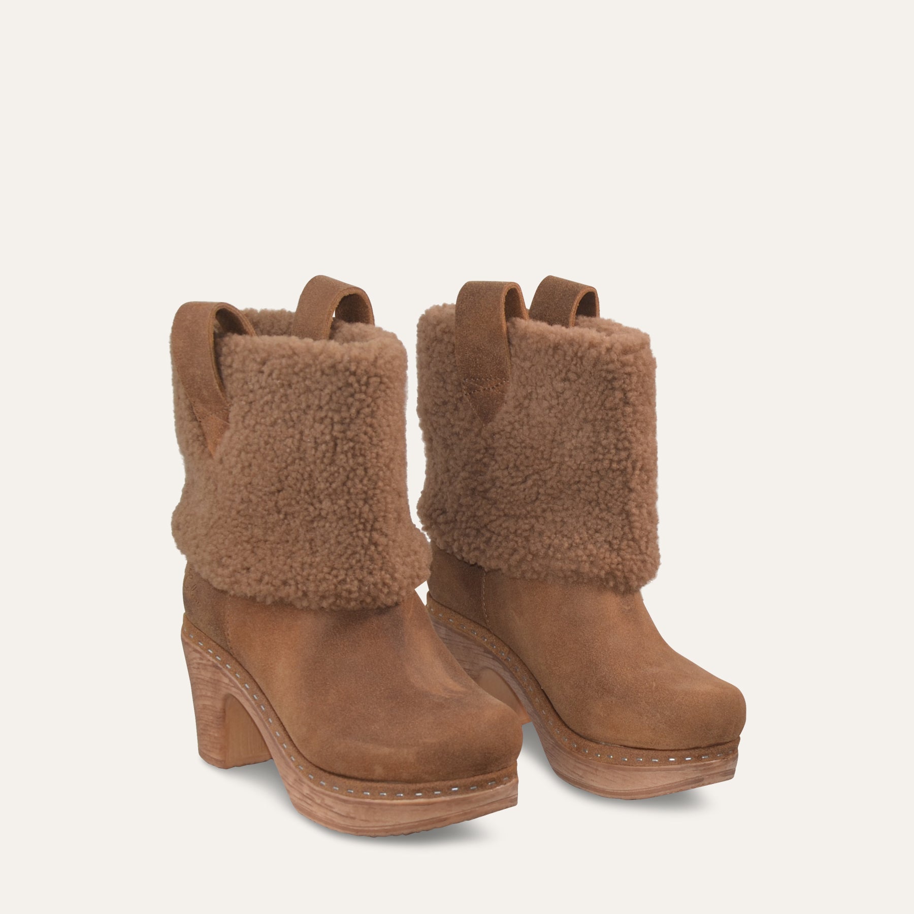 Brown suede boots with fur trim on a light beige background