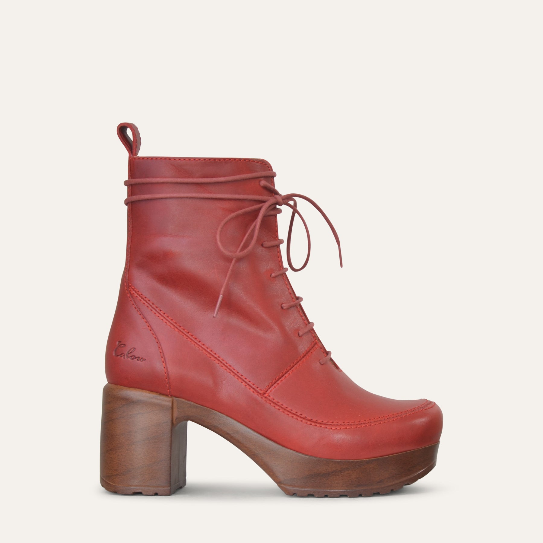 Red leather ankle boot with wood-look heel on a light beige background