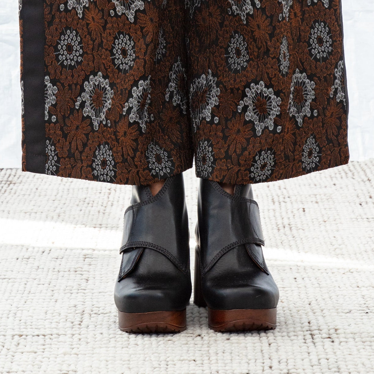 Black leather ankle clog boots with a white background