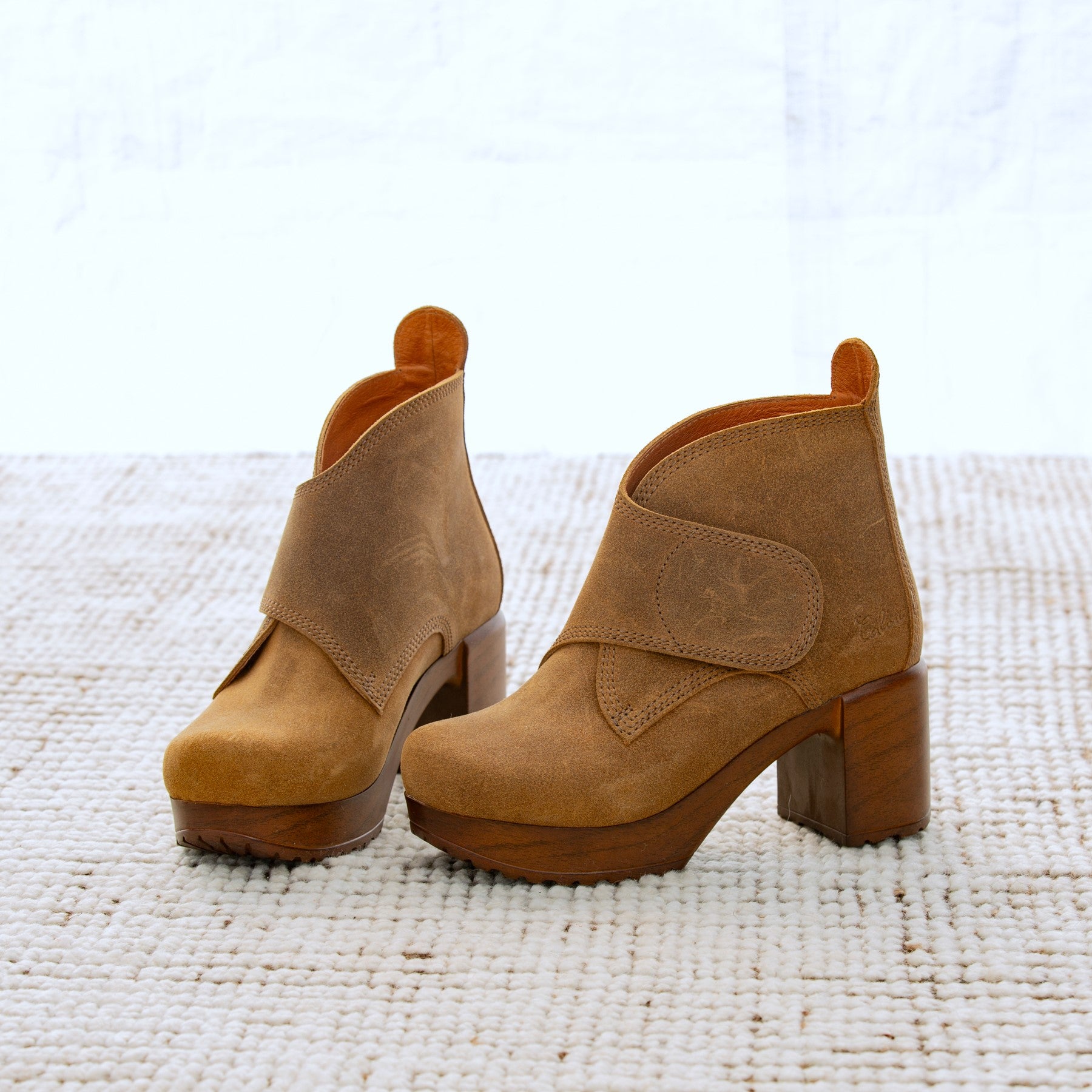 Pair of brown suede ankle boots on a textured white surface