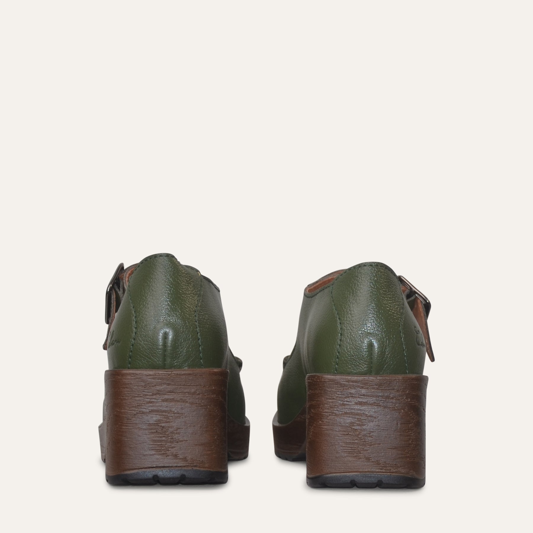 Green leather shoes with brown soles on a white background