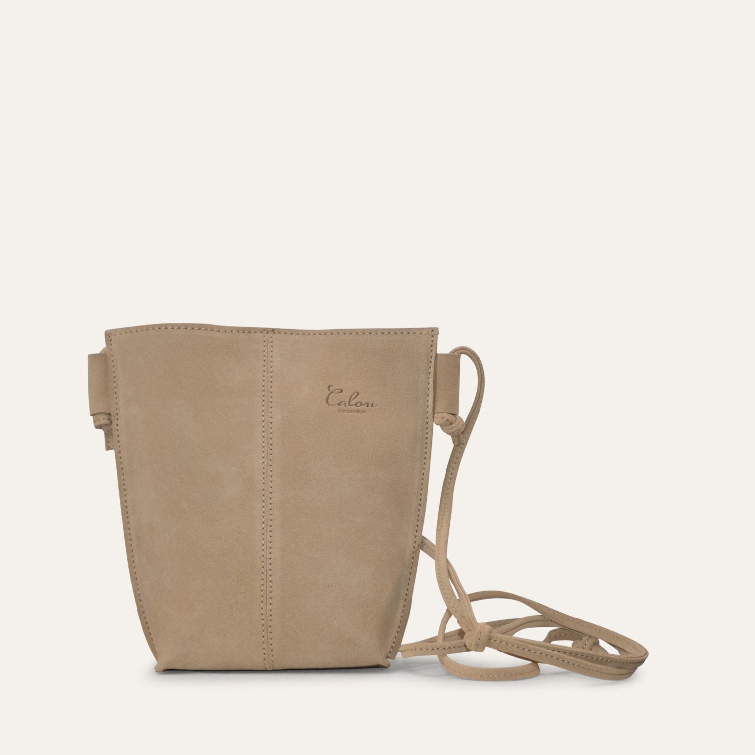 A small shoulder bag with a beige suede exterior, and an adjustable shoulder strap.