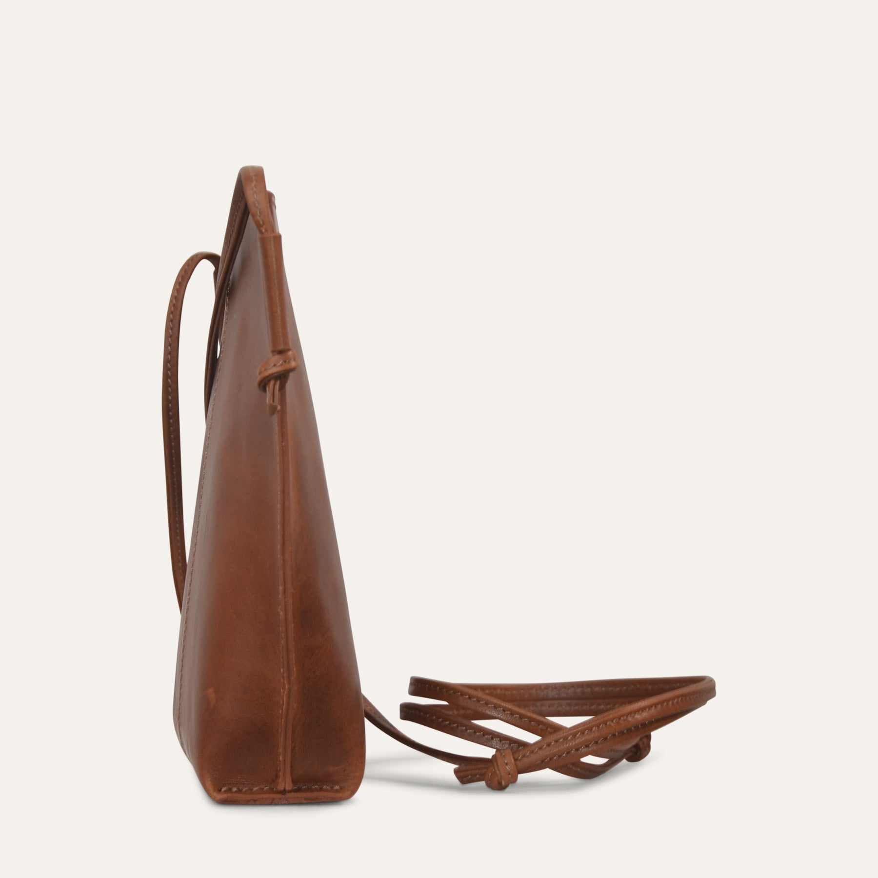 Brown leather handbag with a strap on a light beige background