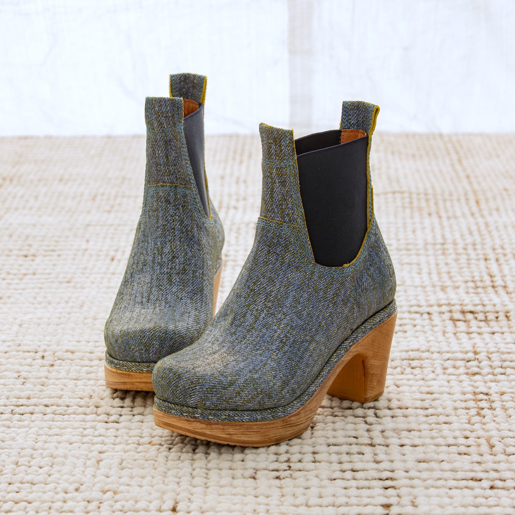 Pair of denim ankle boots with wooden soles on a textured surface