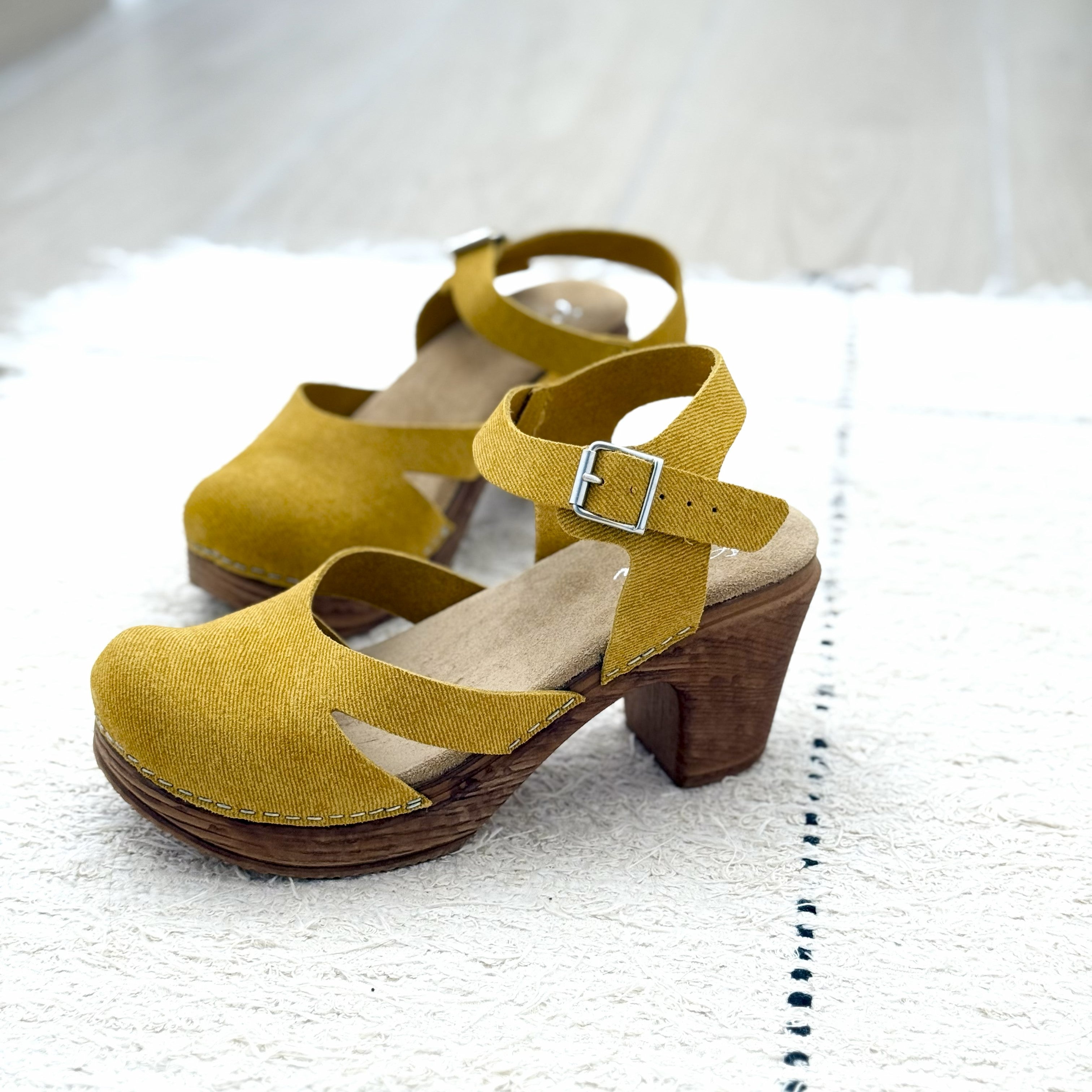 A pair of yellow suede clogs with wood-like effect heels by Calou