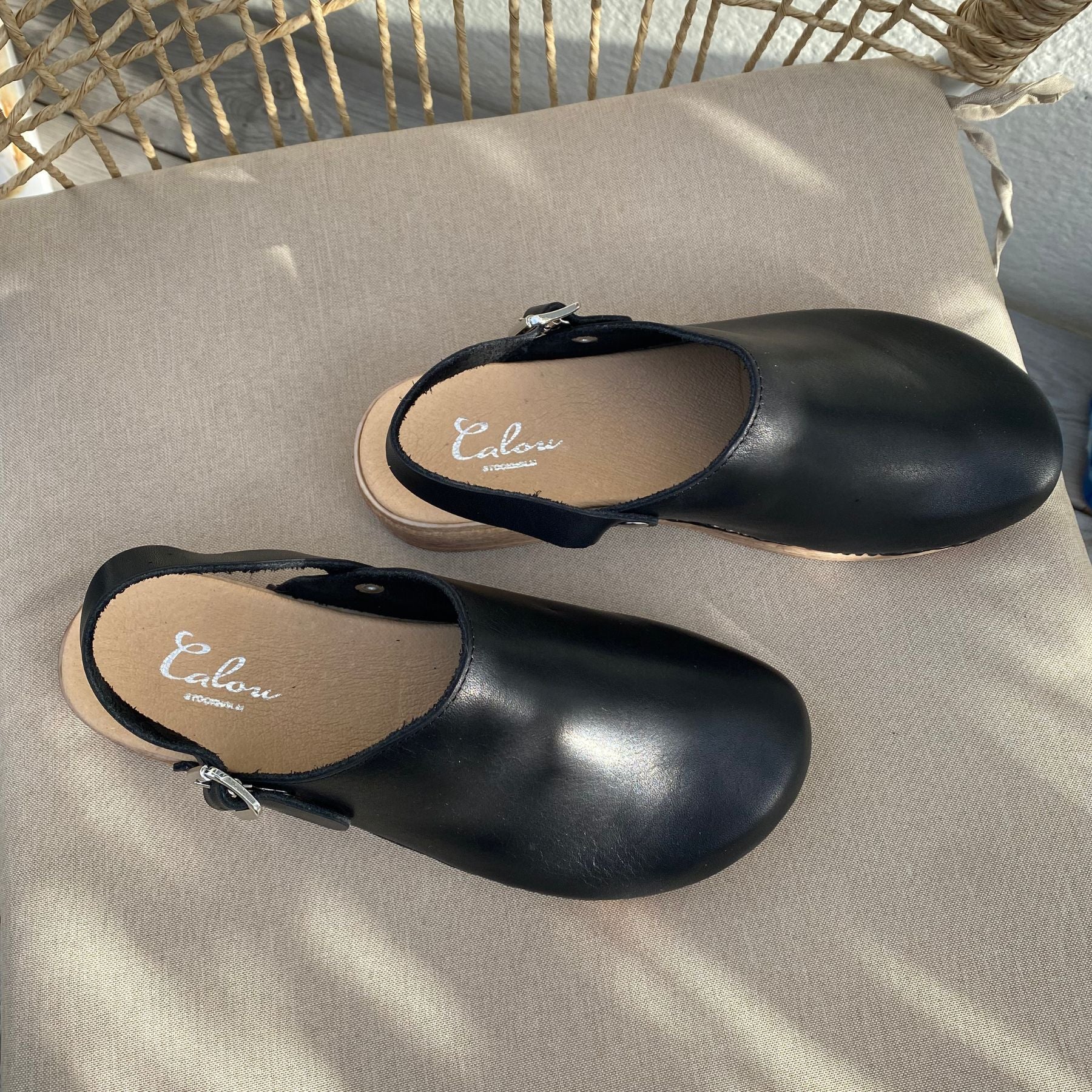 Siri black leather clogs on chair, Calou Stockholm
