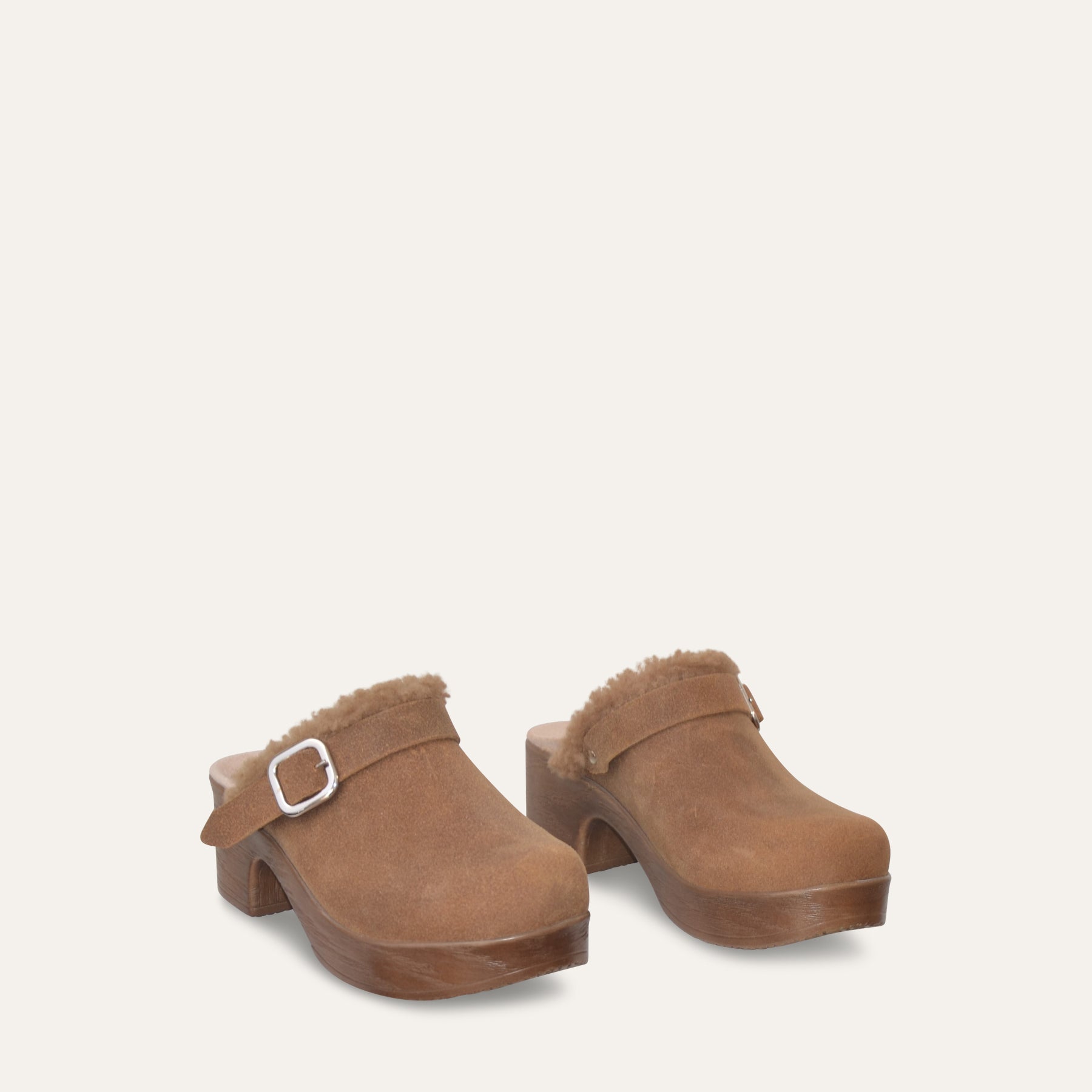 Pair of brown clogs with fur trim on a light gray background