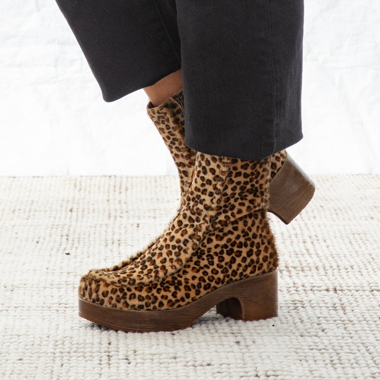 Leopard print boots worn with black pants on a white background