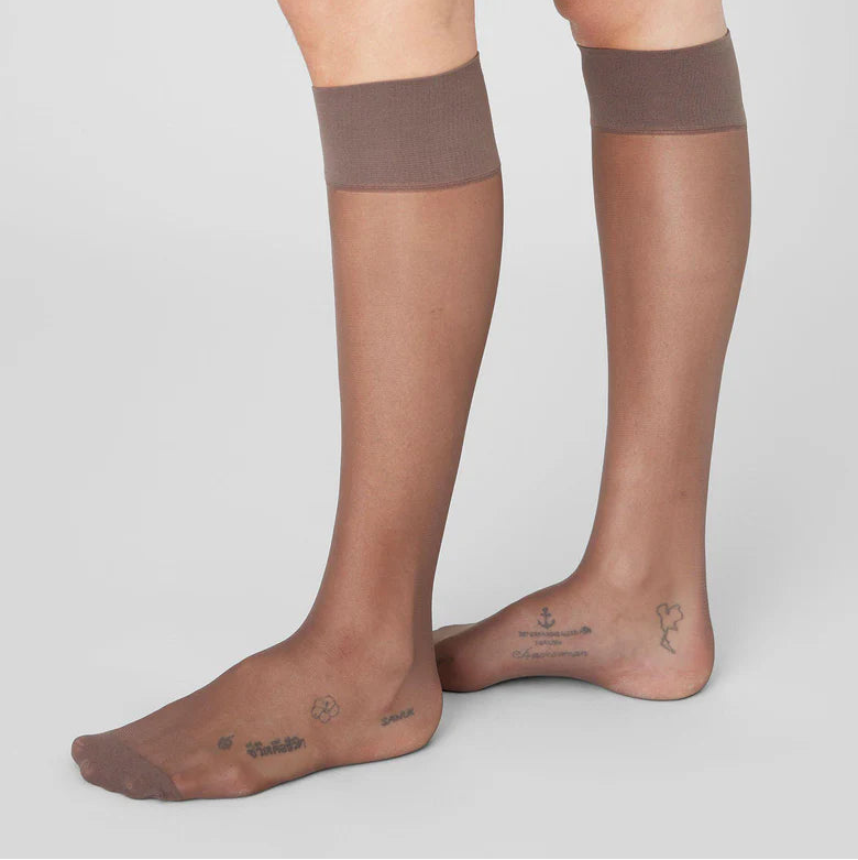 Brown knee-high socks worn by a person on a light gray background