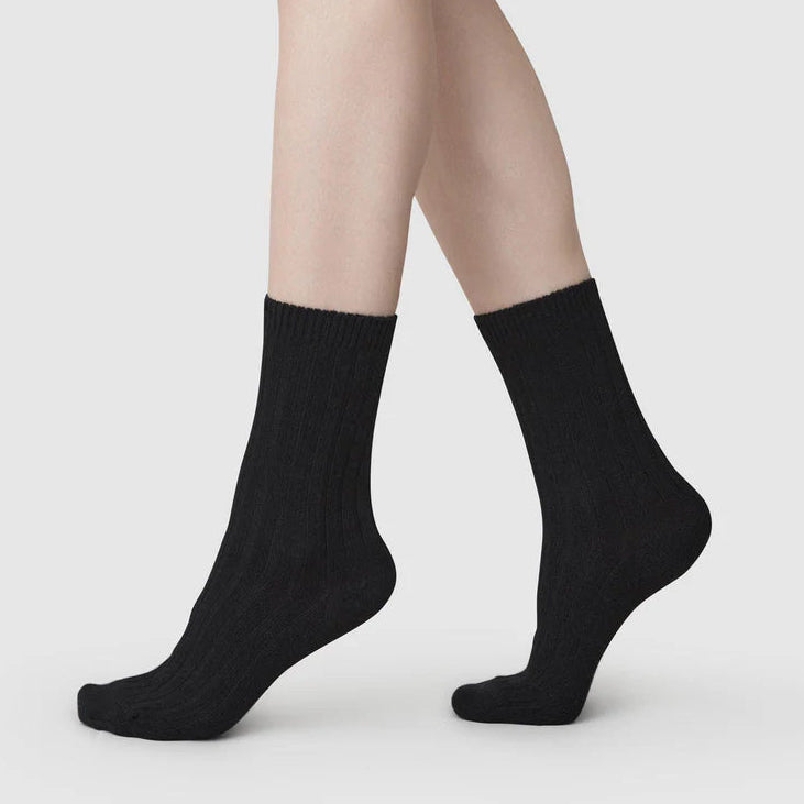 Black socks worn with beige tights on a light gray background