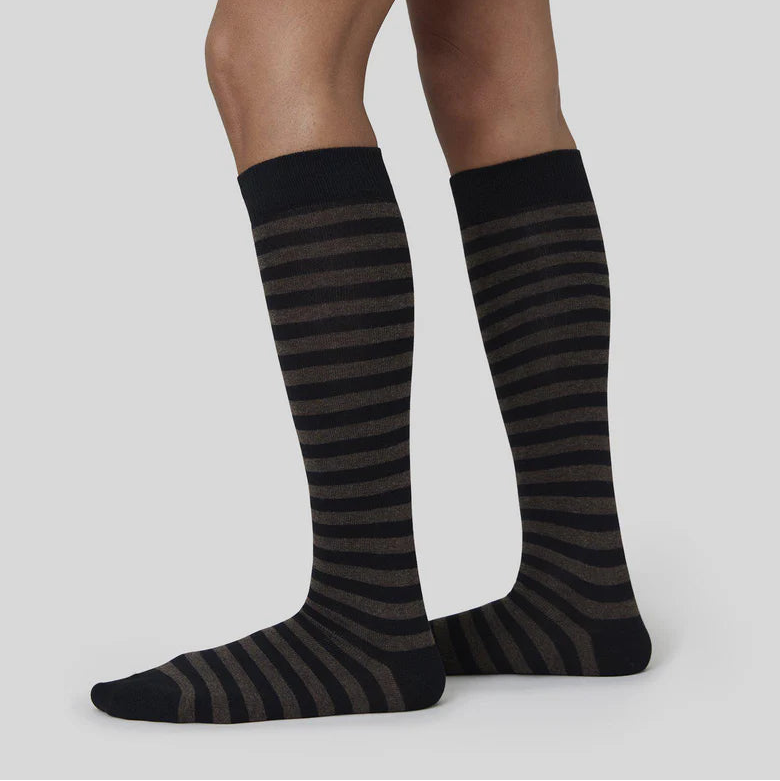 Black and gray striped socks worn by a person on a light gray background