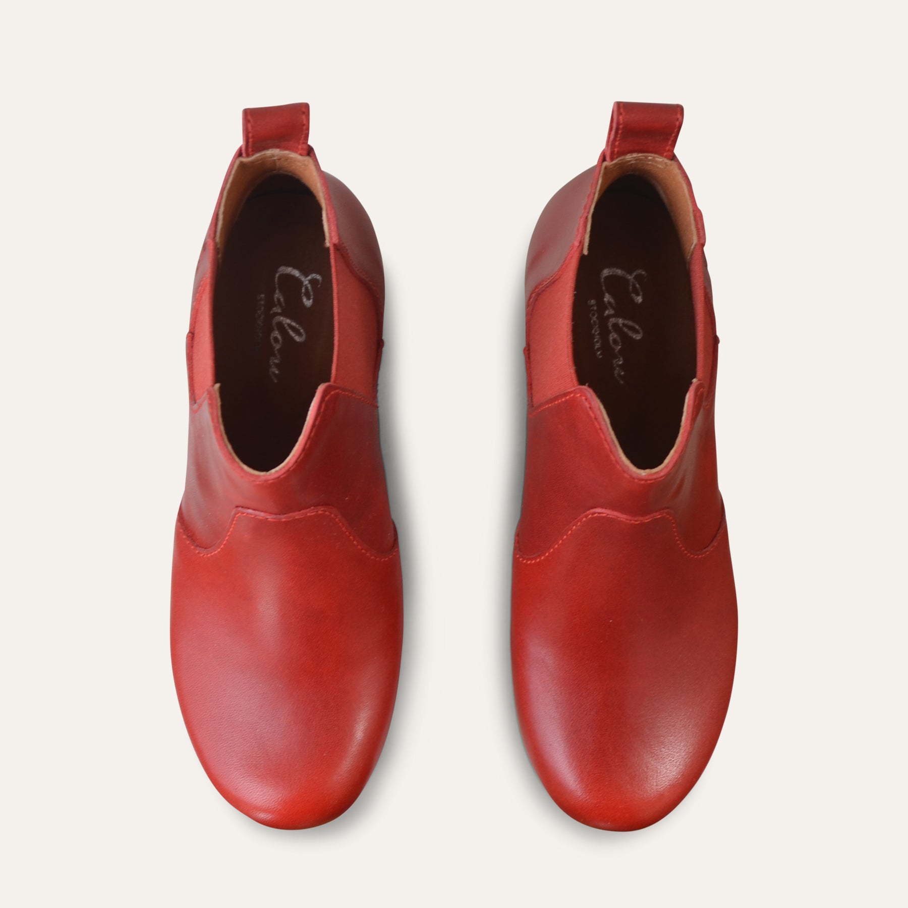Pair of red clog-boots on a light gray background