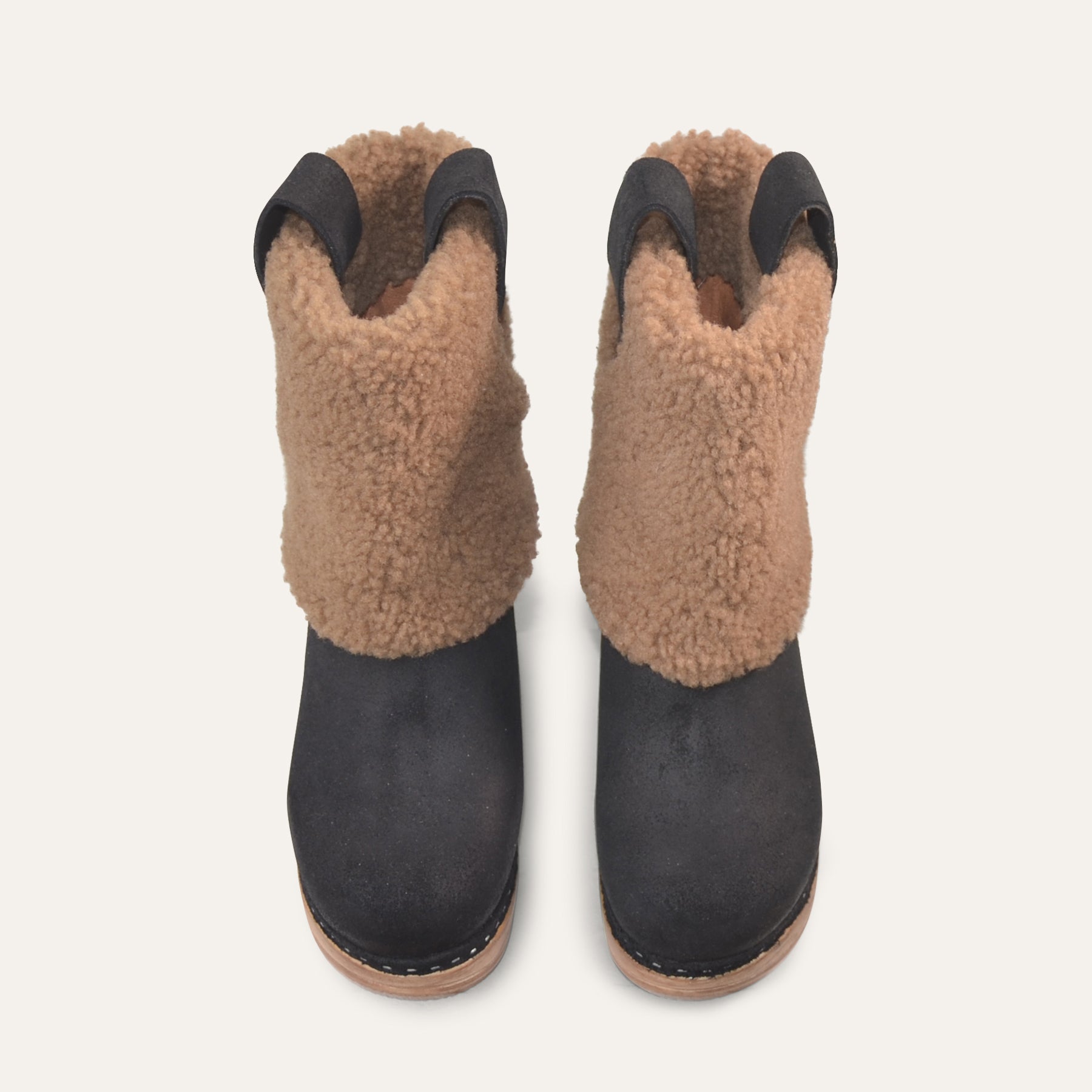Pair of black boots with brown shearling on a white background