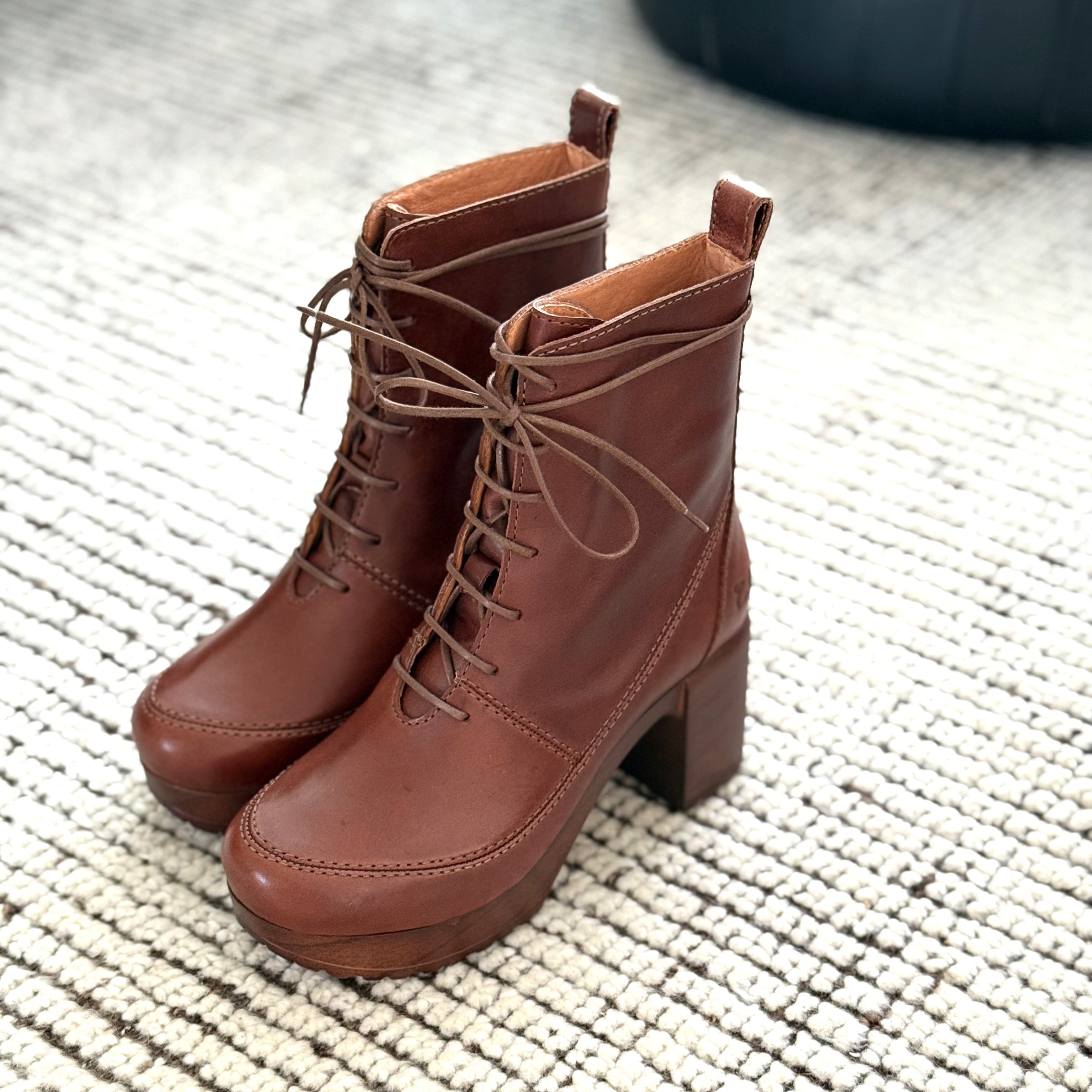 Pair of brown lace-up boots on a textured surface