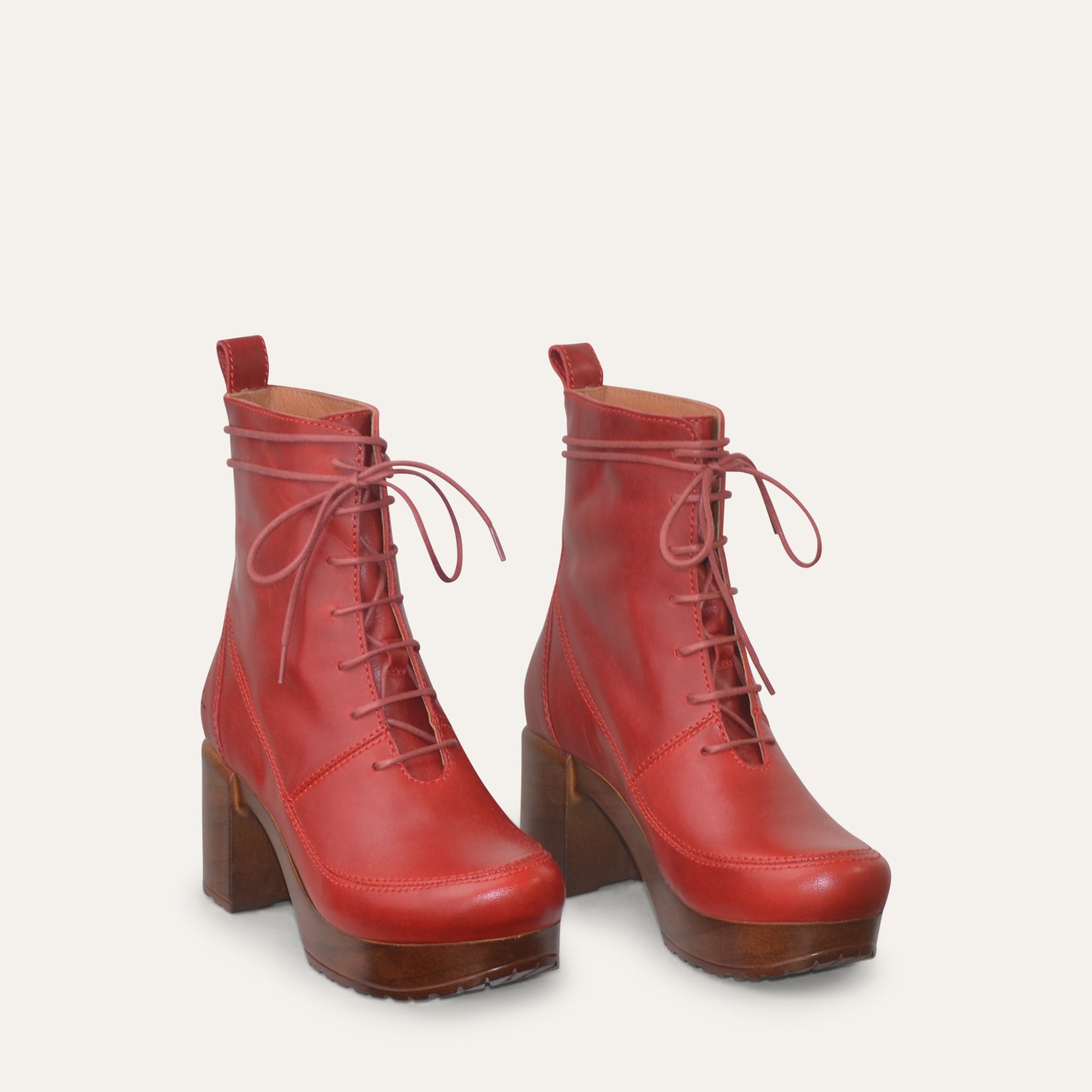 Red leather boots with brown soles on a light gray background