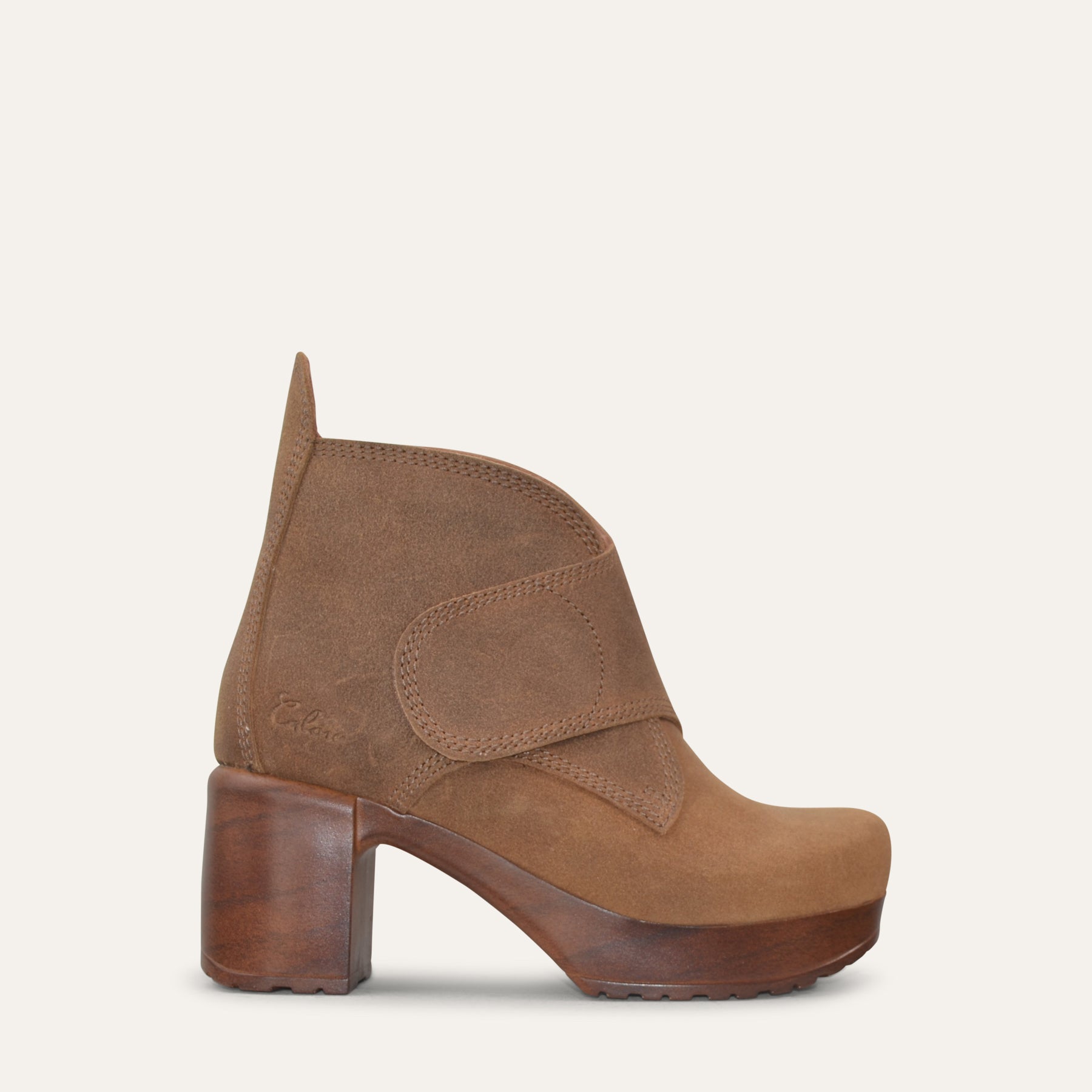 Brown suede ankle boot with wood imitation heel on a light beige background