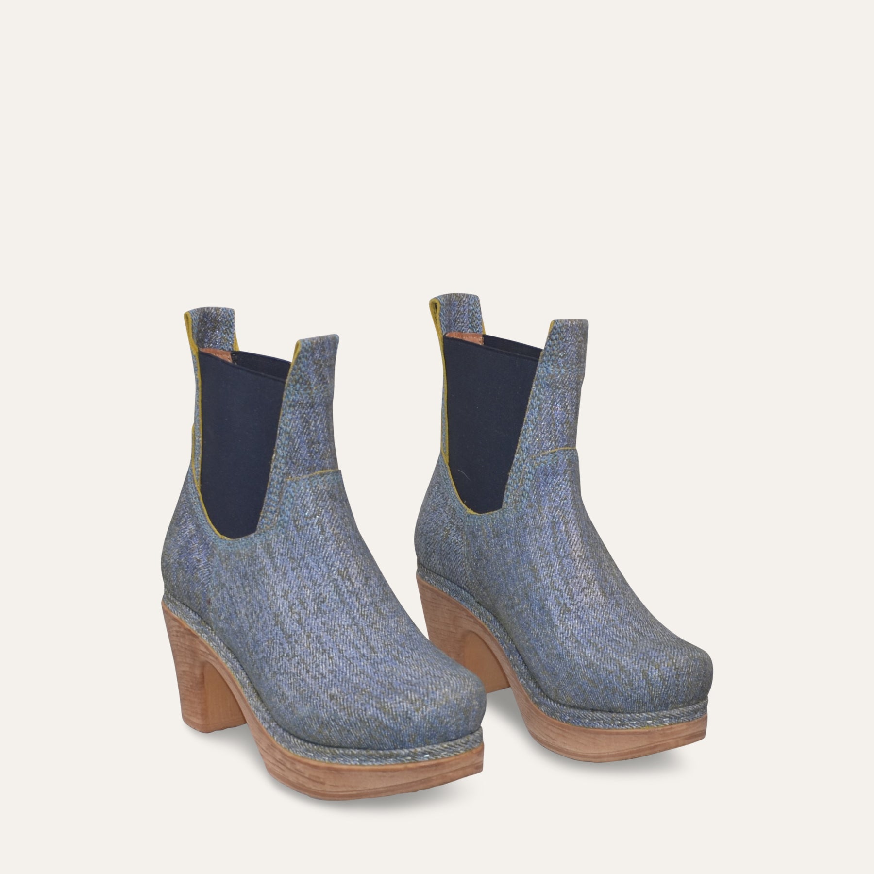 Pair of blue denim ankle boots with woodlike soles on a light gray background