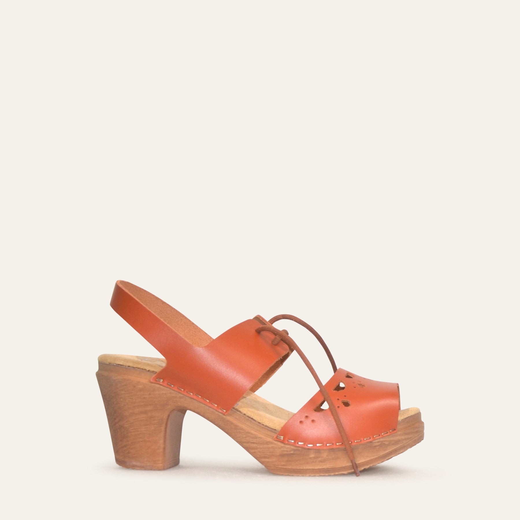 Side view of orange leather clog with wood-look heel and slingback strap by Calou