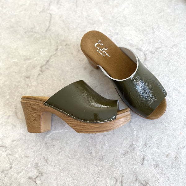 Green patent leather slip on high heel clogs on stone slab