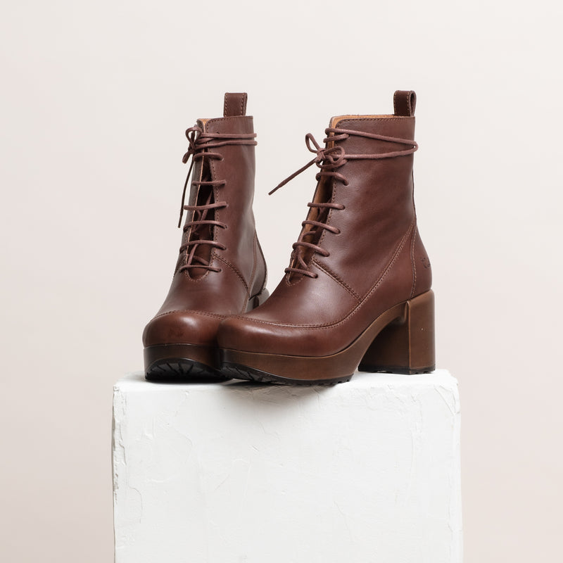 Brown leather lace up clog boots on plinth